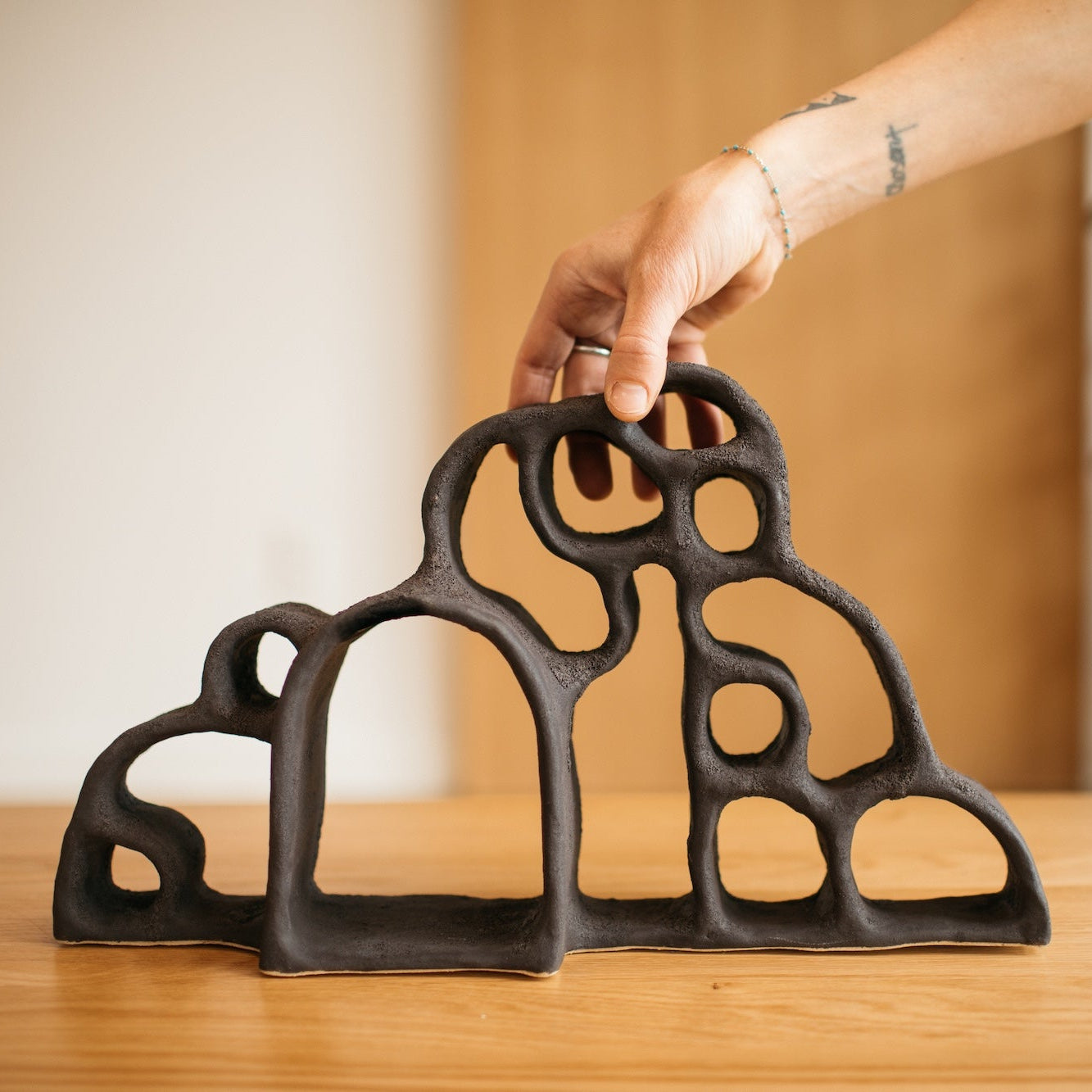 Person holding a decorative black metal object on a wooden surface